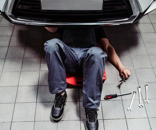 mechanic working on a car using an automotive creeper
